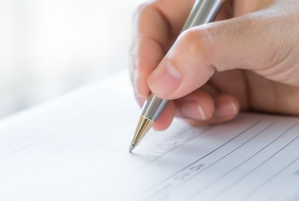 Hand completing a form representing USCIS Form I-924A annual reporting for EB-5 regional centers